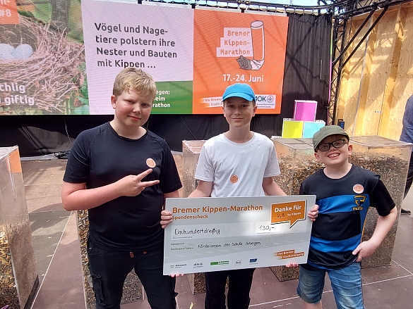 drei Kinder, die den Gewinnerscheck des Bremer Kippen Marathon in der Hand halten